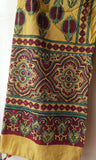 Yellow fabric with intricate red, green, and gold patterns